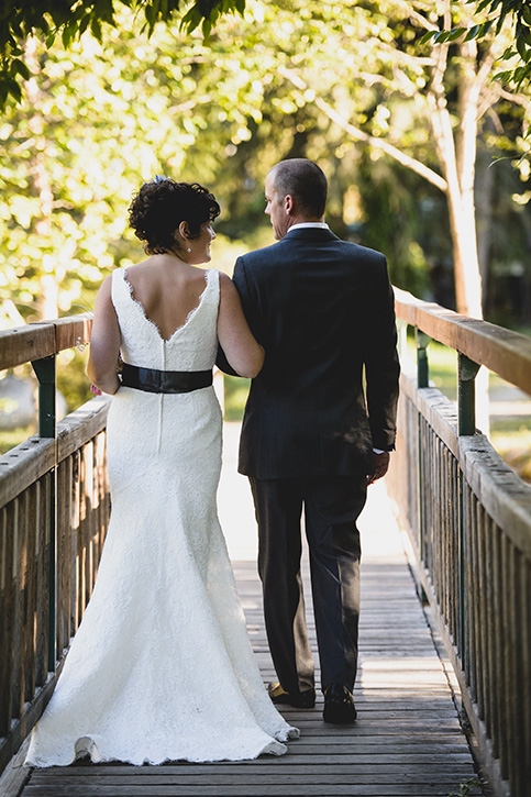 Bride and groom stroll down footbridge at rustic Kootenay Wedding by Electrify Photography.