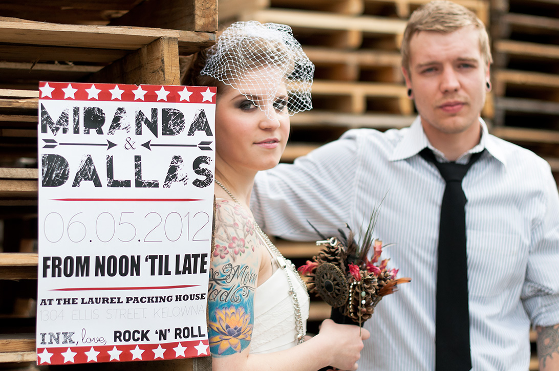 Rock and roll wedding with tattooed couple in back alley, with poster by Kootenay Wedding Photographer Electrify Photography